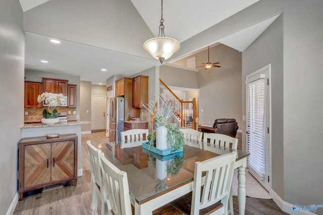 dining area with a ceiling fan, stairway, light wood-type flooring, and baseboards