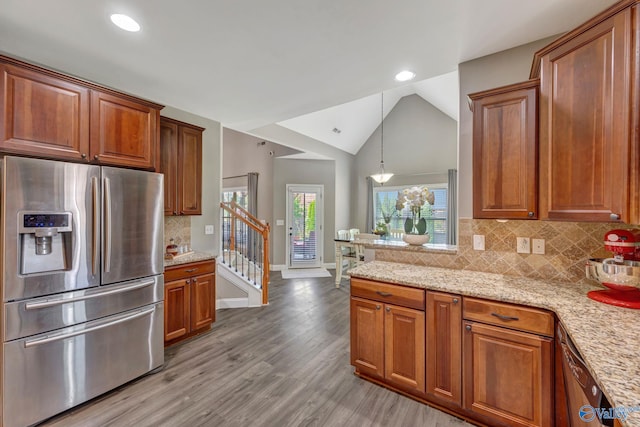 kitchen featuring vaulted ceiling, stainless steel fridge, light wood-type flooring, and brown cabinets