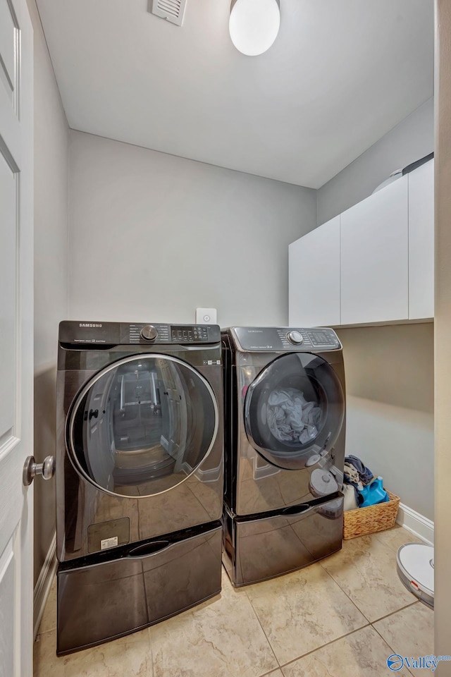 laundry room featuring cabinet space, washer and clothes dryer, visible vents, and baseboards