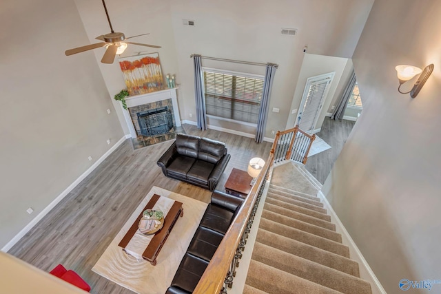 living area with ceiling fan, a towering ceiling, baseboards, and wood finished floors