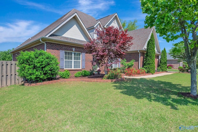 craftsman-style home featuring a front yard, brick siding, a shingled roof, and fence