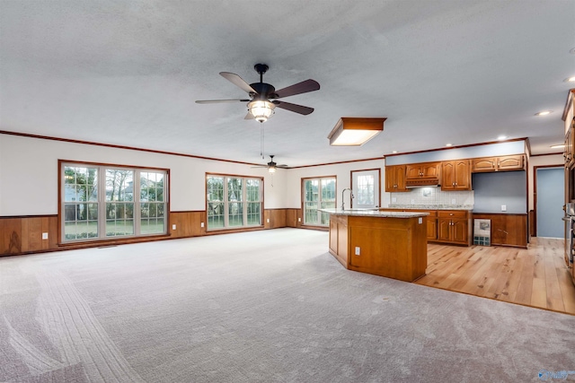 kitchen featuring light stone countertops, ornamental molding, a kitchen island, and light carpet