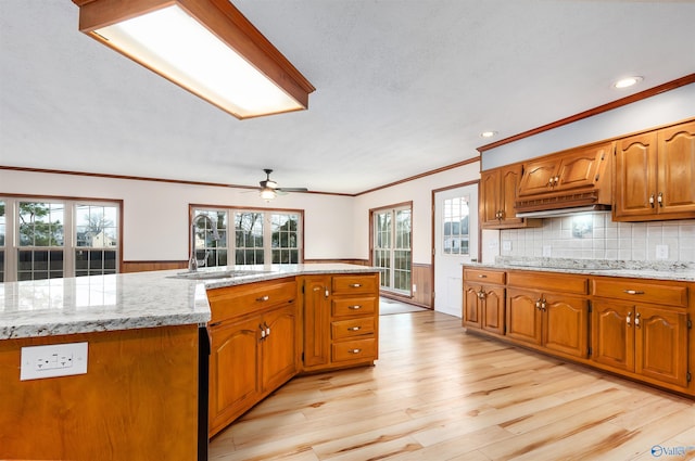 kitchen featuring sink, decorative backsplash, black electric stovetop, light stone counters, and light hardwood / wood-style floors