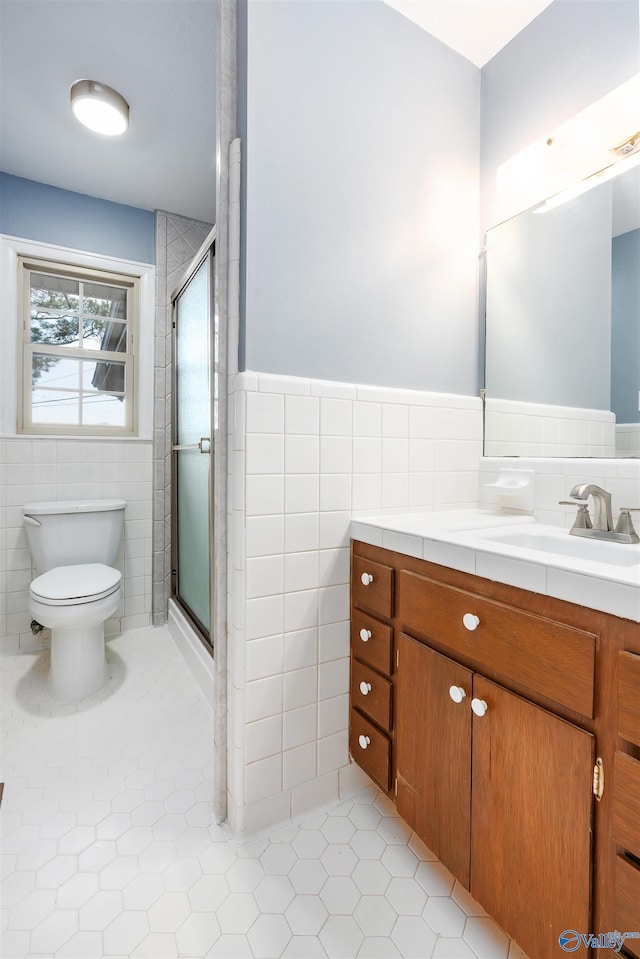 bathroom featuring tile patterned floors, a shower with door, tile walls, and vanity