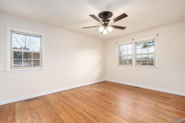 empty room with ceiling fan, plenty of natural light, and light wood-type flooring