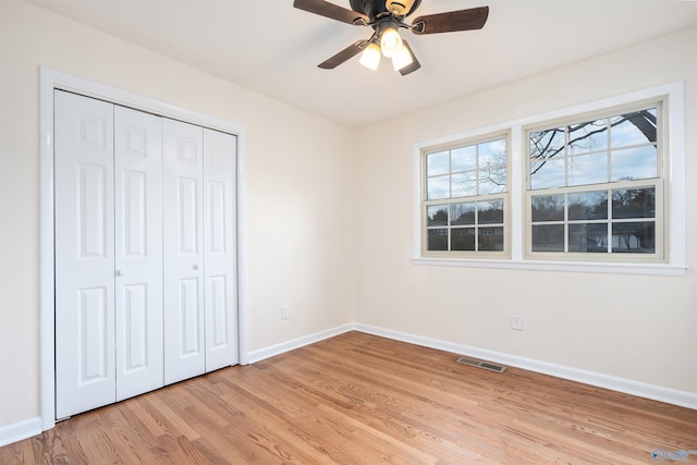 unfurnished bedroom with ceiling fan, a closet, and light wood-type flooring