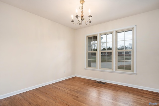 spare room with wood-type flooring and a chandelier