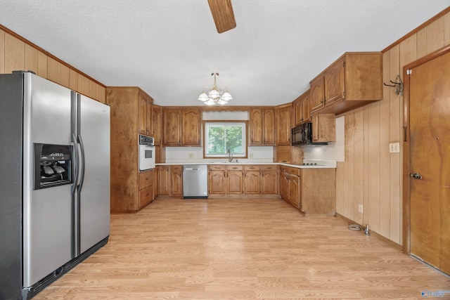 11303 Crestfield Dr, Huntsville, AL 35803 - kitchen featuring black appliances, light wood-type flooring, a sink, light countertops, and wood walls