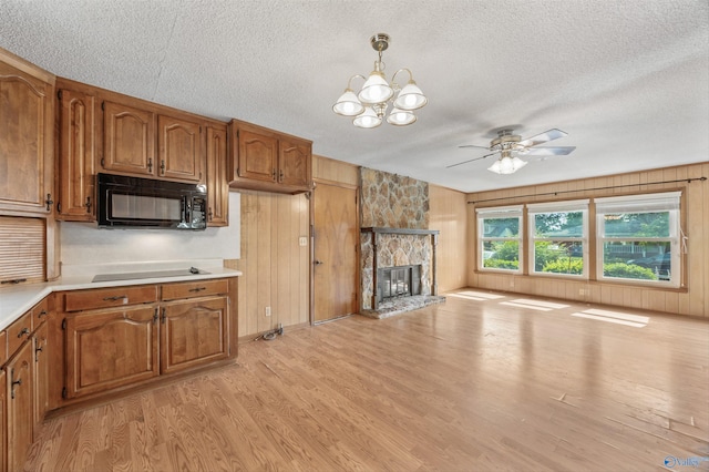 11303 Crestfield Dr, Huntsville, AL 35803 - kitchen with black microwave, a textured ceiling, brown cabinets, light wood-style flooring, and light countertops