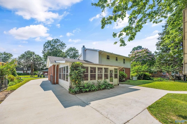 11303 Crestfield Dr, Huntsville, AL 35803 - rear view of house featuring a yard, a chimney, a sunroom, brick siding, and driveway