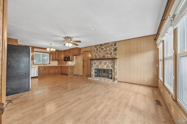 11303 Crestfield Dr, Huntsville, AL 35803 - unfurnished living room featuring a textured ceiling, a stone fireplace, light wood-style flooring, a sink, and wooden walls