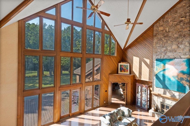 living room with high vaulted ceiling, wood walls, and ceiling fan