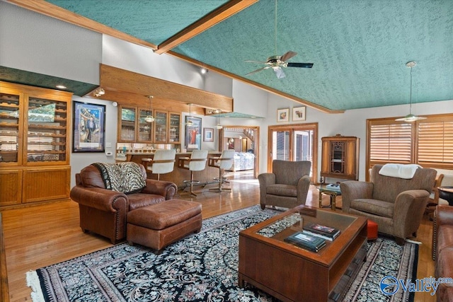 living room with high vaulted ceiling, hardwood / wood-style floors, beam ceiling, and ceiling fan