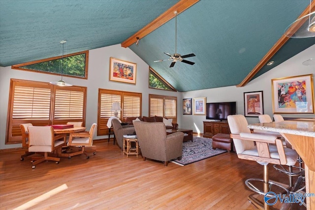 living room with high vaulted ceiling, hardwood / wood-style floors, beam ceiling, and ceiling fan