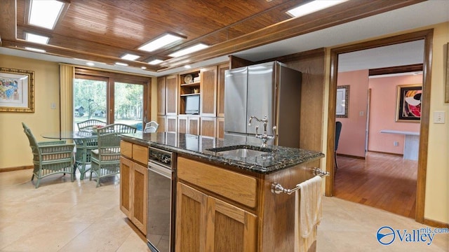 kitchen featuring wood ceiling, an island with sink, dark stone counters, and sink