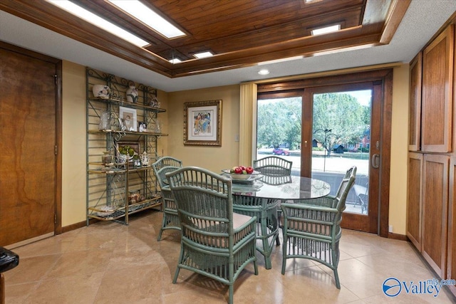 dining area with a raised ceiling and wooden ceiling