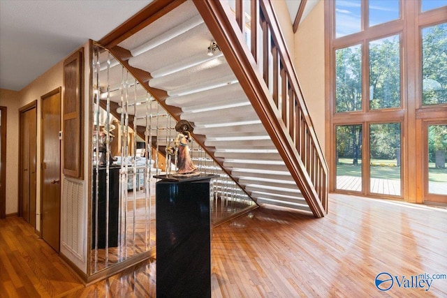 stairway with hardwood / wood-style flooring and a high ceiling