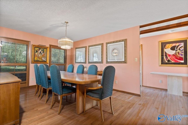 dining space featuring a chandelier, a textured ceiling, and light hardwood / wood-style flooring