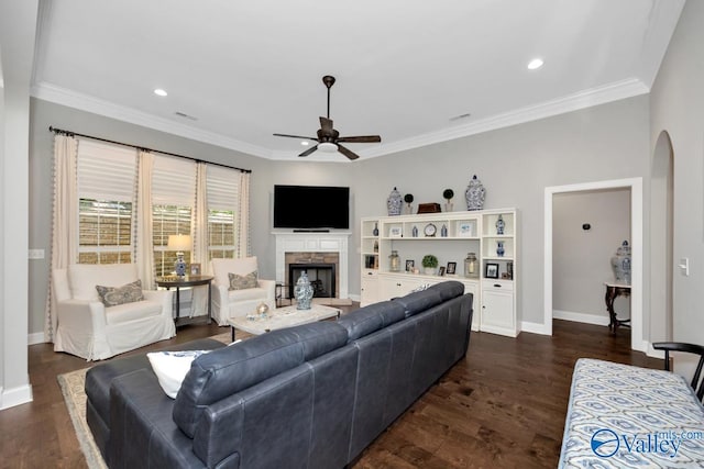 living room featuring dark wood finished floors, a fireplace with raised hearth, baseboards, and ceiling fan