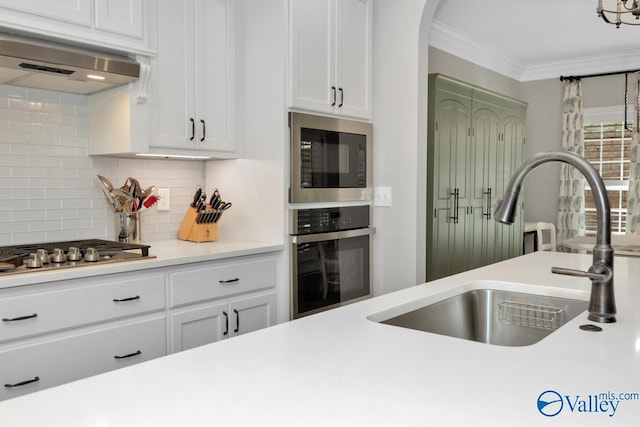 kitchen featuring oven, a sink, built in microwave, stainless steel gas stovetop, and under cabinet range hood