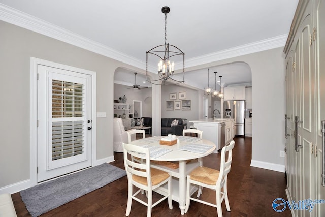 dining room featuring arched walkways, crown molding, baseboards, and ceiling fan with notable chandelier