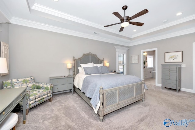carpeted bedroom with a tray ceiling, visible vents, a ceiling fan, ensuite bath, and ornamental molding