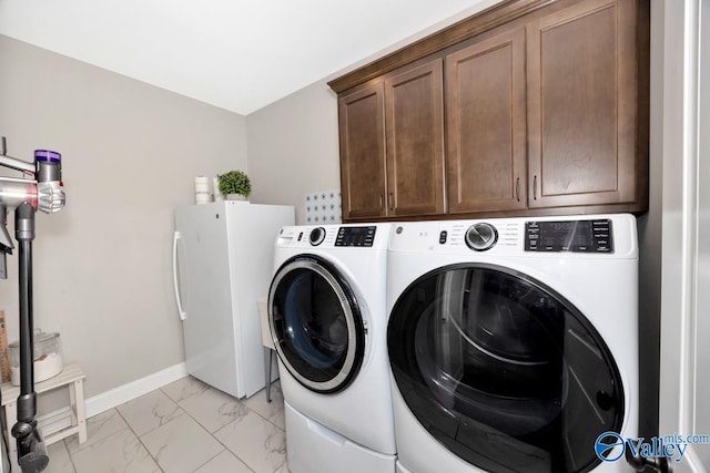 washroom with washing machine and dryer, baseboards, marble finish floor, and cabinet space