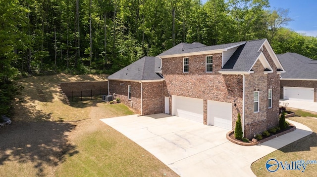 exterior space featuring fence, a shingled roof, concrete driveway, an attached garage, and brick siding