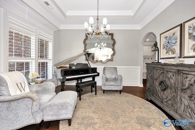 sitting room featuring wood finished floors, a chandelier, arched walkways, a tray ceiling, and visible vents