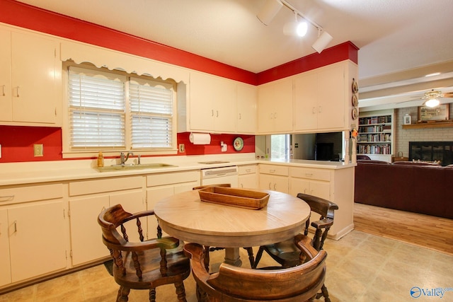 kitchen featuring a healthy amount of sunlight, ceiling fan, sink, and a brick fireplace