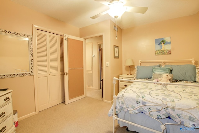 bedroom with light colored carpet, ceiling fan, and a closet