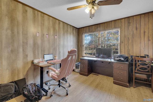 home office featuring light wood-type flooring, ceiling fan, and wood walls