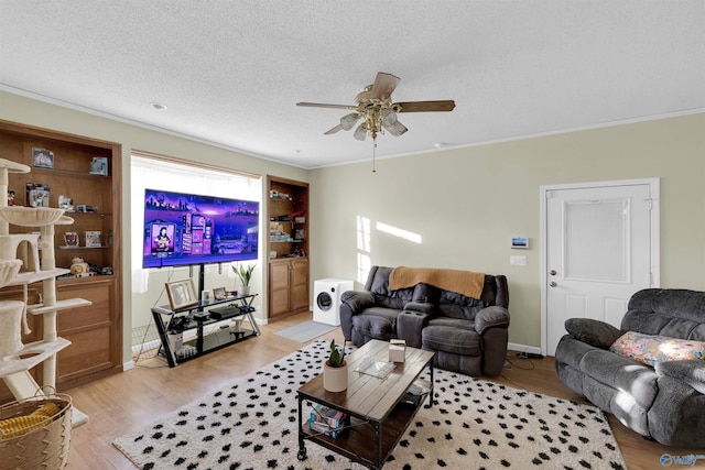 living room featuring ceiling fan, light wood-type flooring, a textured ceiling, and ornamental molding