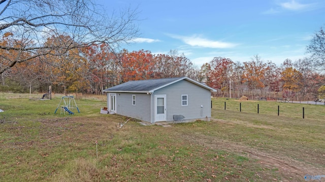 view of side of property with a rural view, an outbuilding, and a yard