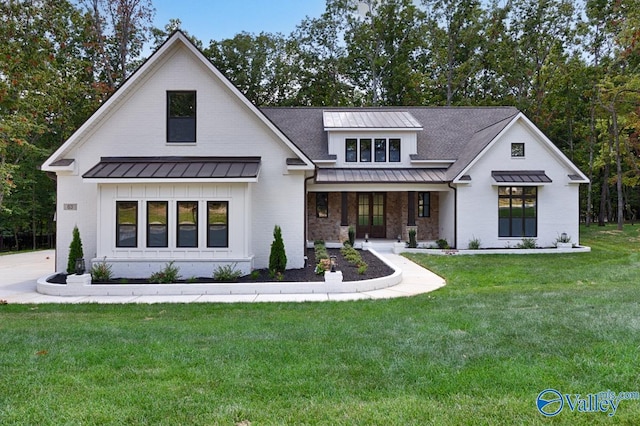 modern farmhouse style home featuring a standing seam roof, board and batten siding, covered porch, a front yard, and metal roof