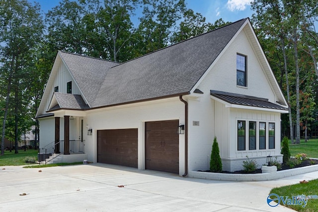 modern inspired farmhouse featuring roof with shingles, a standing seam roof, an attached garage, board and batten siding, and metal roof