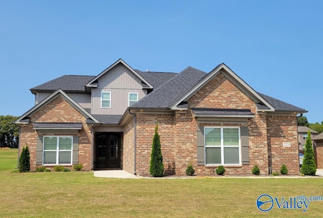 craftsman house with brick siding, board and batten siding, a front yard, and a shingled roof