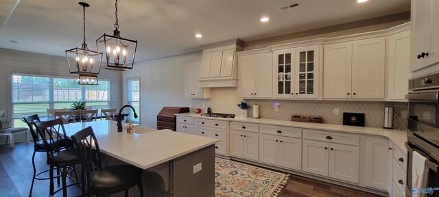 kitchen featuring white cabinets, a center island with sink, a kitchen bar, and dark hardwood / wood-style flooring