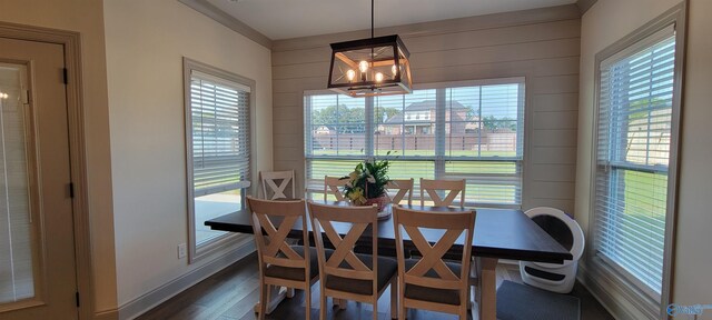 dining area featuring wooden walls, dark wood-type flooring, and a notable chandelier