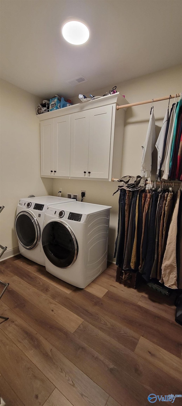 clothes washing area featuring cabinets, dark hardwood / wood-style flooring, and washing machine and clothes dryer