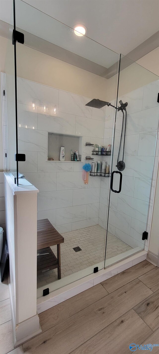 bathroom with hardwood / wood-style floors, a shower with shower door, and toilet