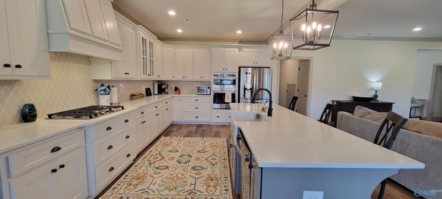 kitchen with white cabinets, a breakfast bar, stainless steel appliances, premium range hood, and a kitchen island with sink