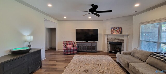 living room with a fireplace, ceiling fan, and dark wood-type flooring