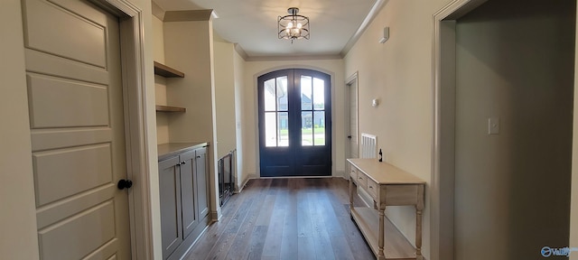 doorway to outside featuring crown molding, dark hardwood / wood-style flooring, a chandelier, and french doors