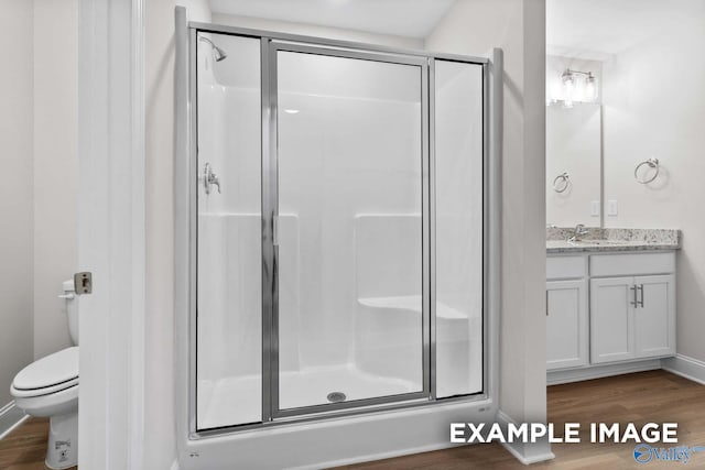 bathroom featuring an enclosed shower, vanity, toilet, and hardwood / wood-style floors