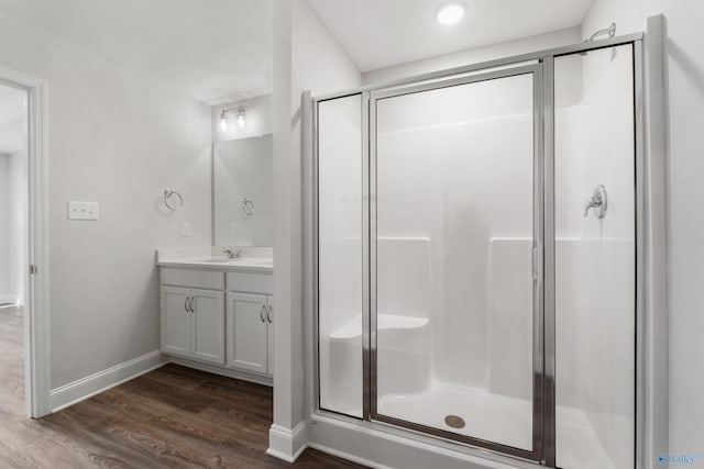 bathroom featuring wood-type flooring, an enclosed shower, and vanity