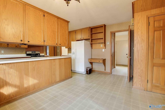 kitchen featuring backsplash, stainless steel electric range, white refrigerator with ice dispenser, and kitchen peninsula