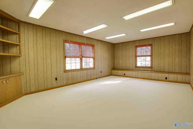 spare room with built in shelves, wood walls, and carpet floors