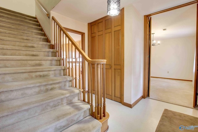 stairs featuring concrete floors and an inviting chandelier