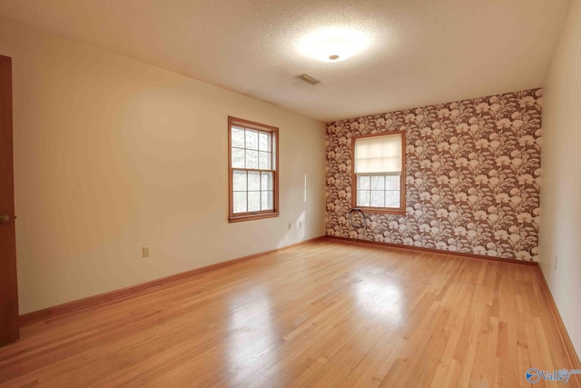 spare room featuring light hardwood / wood-style floors and a textured ceiling